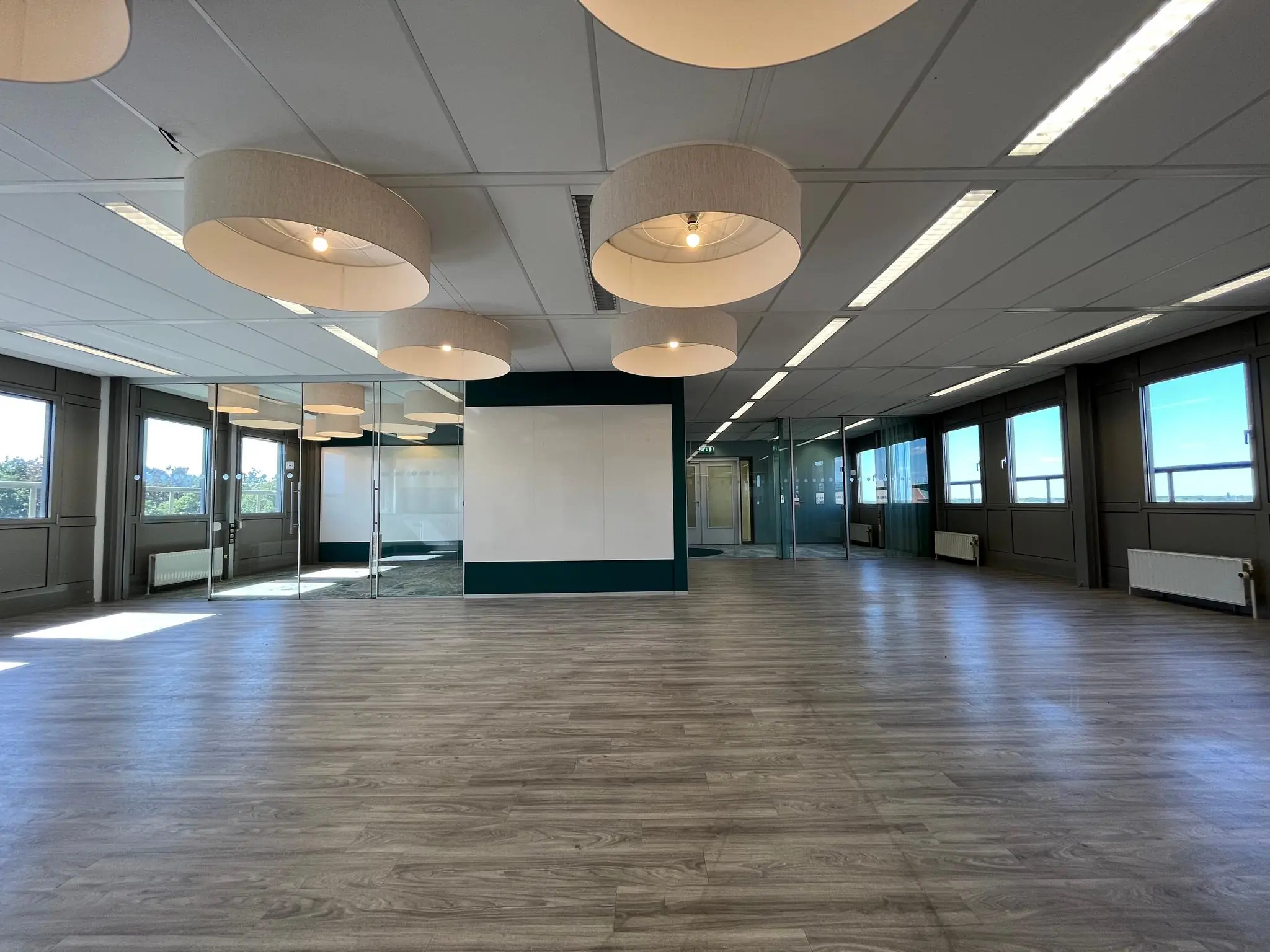 Licht en modern kantoorinterieur aan de Barchman Wuytierslaan met grote ramen, glazen wanden en houten vloer.